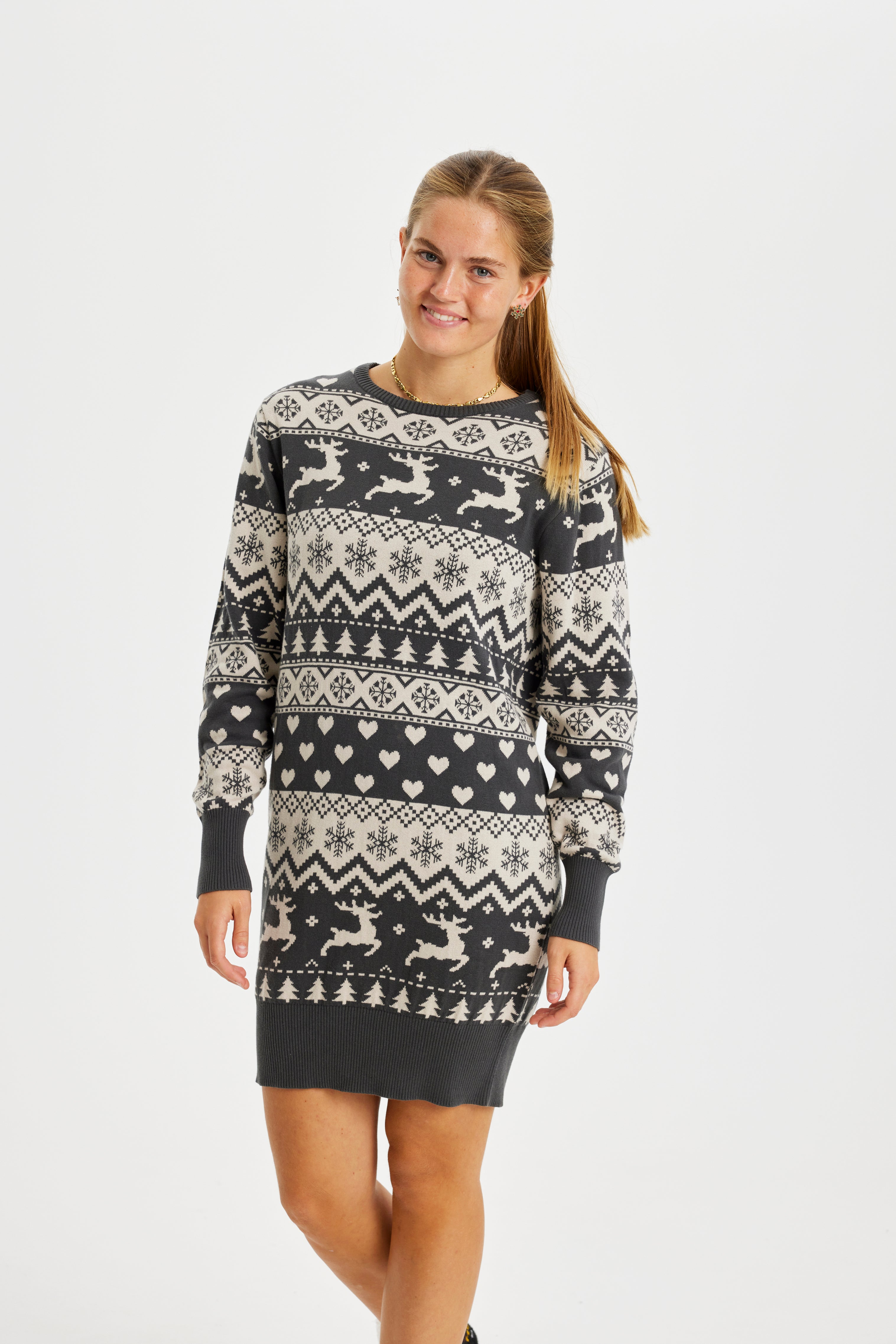 Een glimlachende vrouw draagt een grijze kerstjurk.